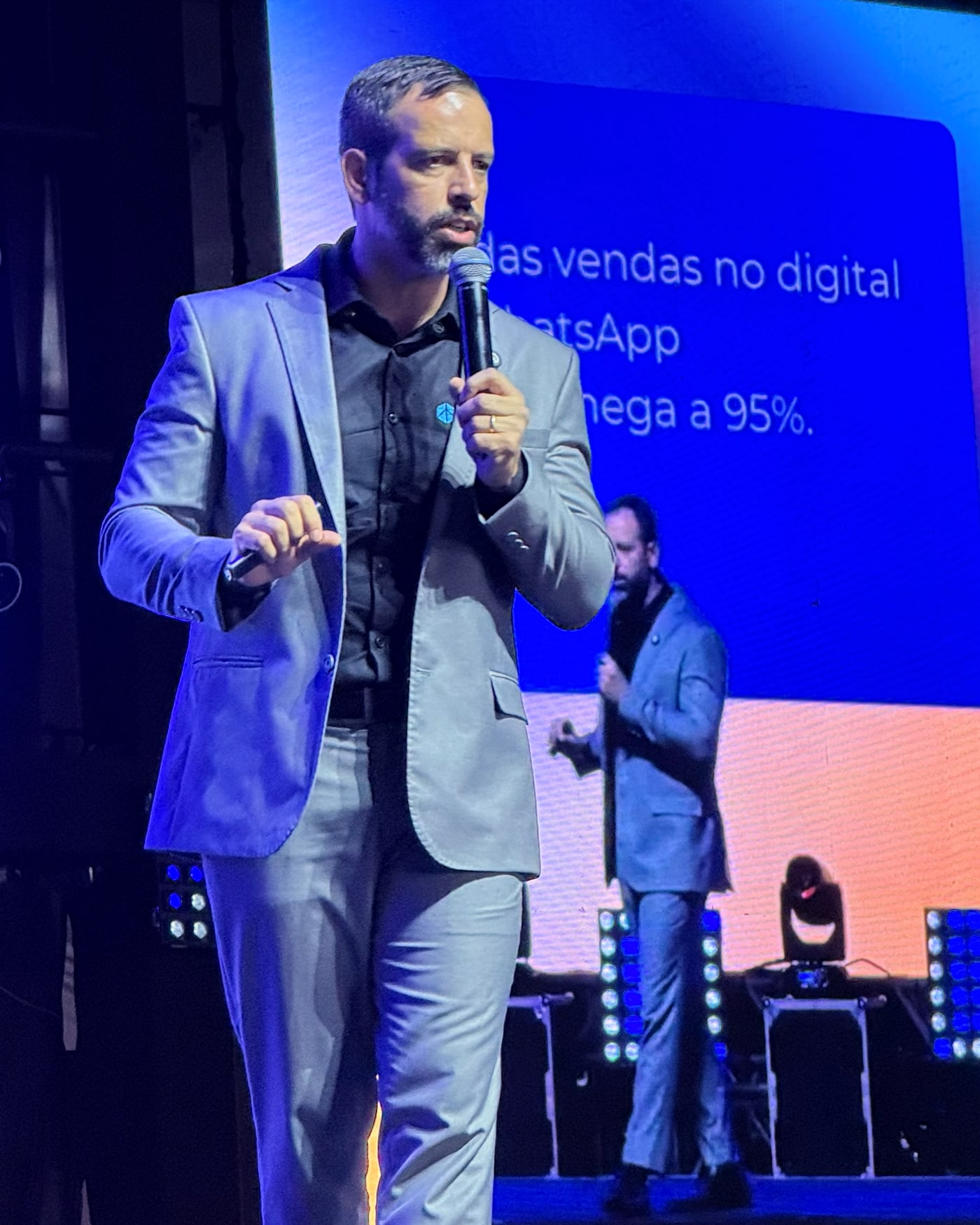 Rafael Tonietto no palco, de blazer, falando ao microfone