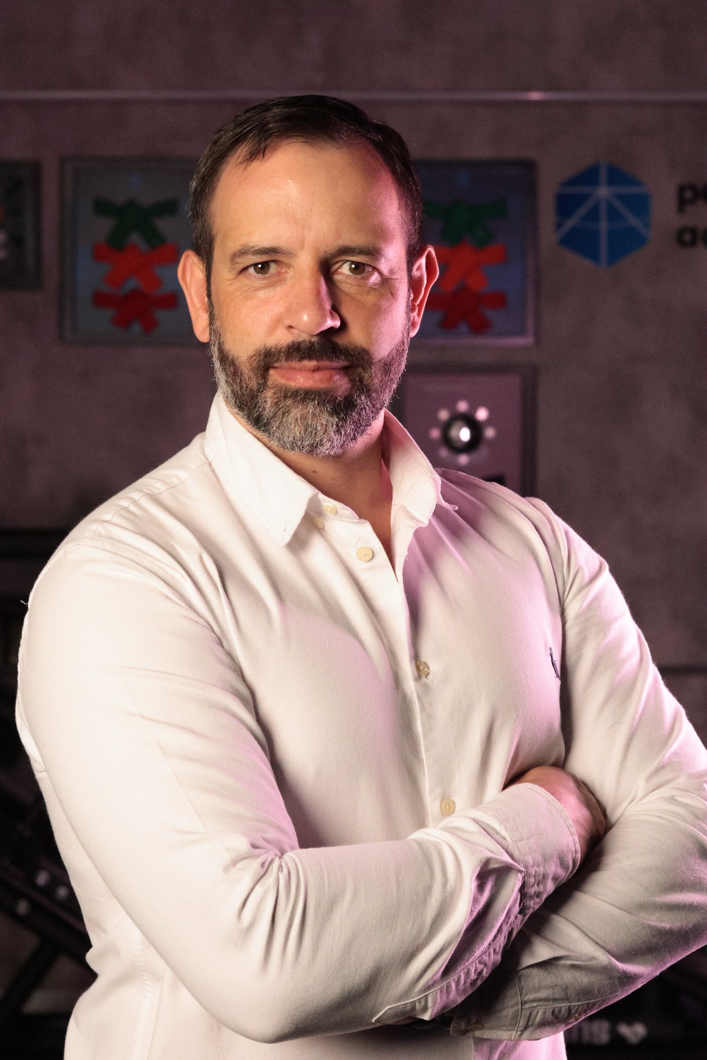 Retrato de Rafael Tonietto, de camisa branca e braços cruzados, sério