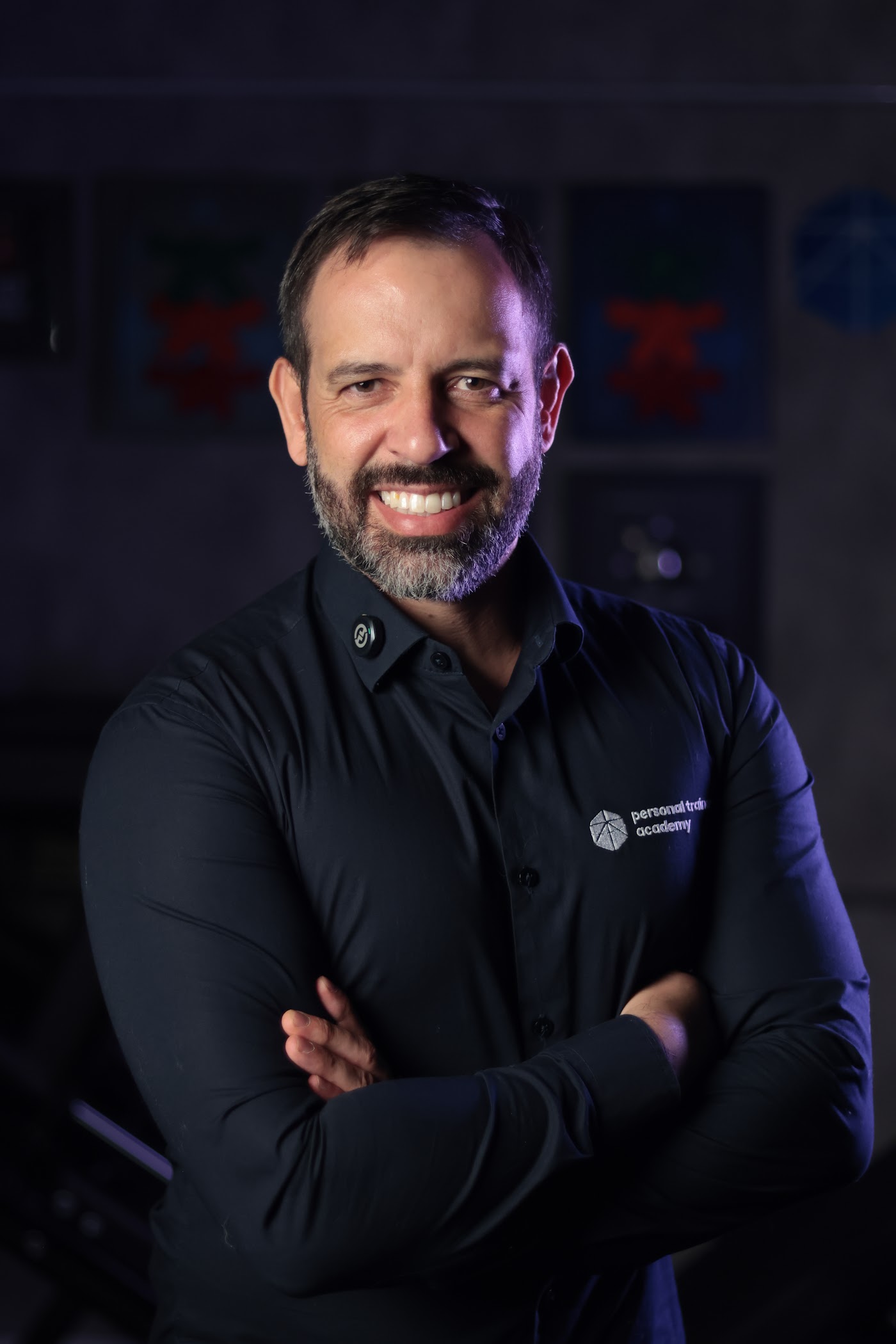 Rafael Tonietto sorrindo, de camisa preta com o logo da Personal Trainer Academy